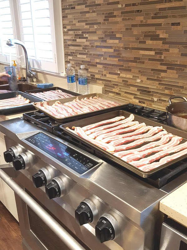 Trays and trays of uncooked bacon sit on the oven and await being cooked and then devoured.