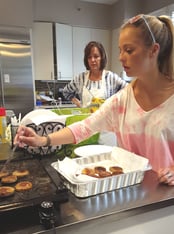 Ashlyn takes the cooked sausage patties from the electric griddle and places them on a paper towel as Lisa looks on and demonstrates more self-restraint than I have when it comes to breakfast foods.