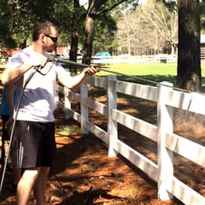 Marcel power washes a fence