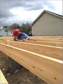 Jeff inspects the wooden board before hammering a nail.