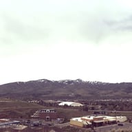An overcast sky looms over the mountains behind the school buildings.