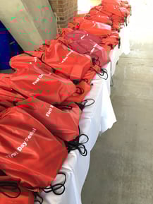 Red drawstring bags line a table.