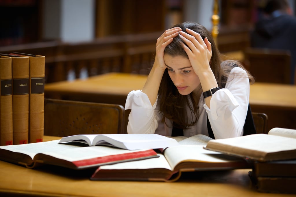 Stressed-out student stares at a pile of books.