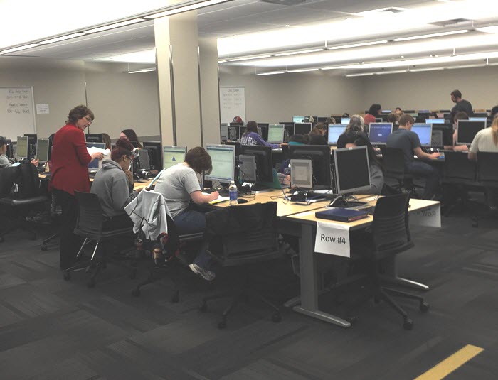 The picture shows a lab of about a hundred computers on several desks with students doing work.