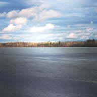 Frozen lake in Minnesota in front of a quiet wooded area.