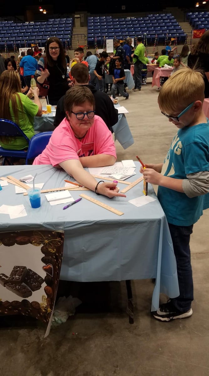 An instructor shows a child how to make mathematical art.