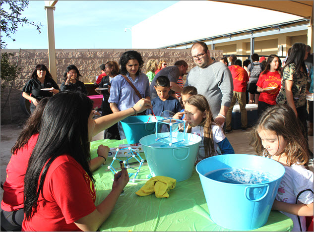Participants blow into cube-shaped bubble contraptions.