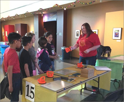 A volunteer and young attendee are about to see how pressure, not suction, keeps the Pressure Pullers together.