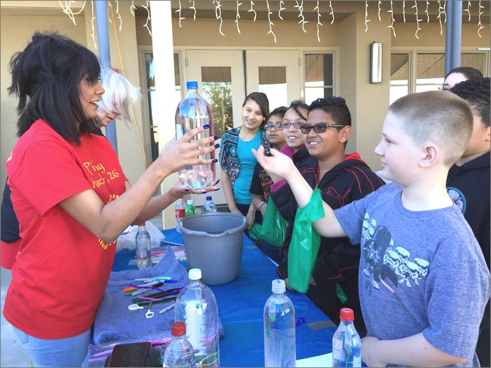 A volunteer shows a young participant his Cartesian diver inside a 2-liter bottle of water.